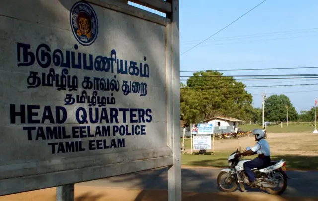 2006 ජනවාරි 24 වන දින කිලිනොච්චියේ පිහිටි දෙමළ ඊළාම් විමුක්ති කොටි (LTTE) මූලස්ථානය පසුකර යන පොලිස් යතුරුපැදිකරුවෙක්.