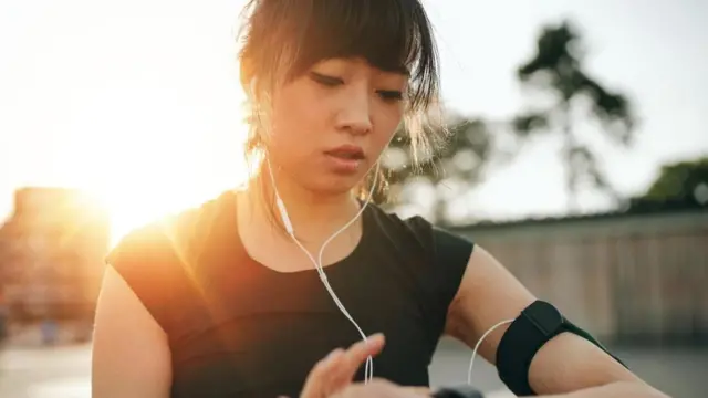 મોબાઇલના ઇઅરફોન પર કંઈક સાંભળતી એક યુવતી