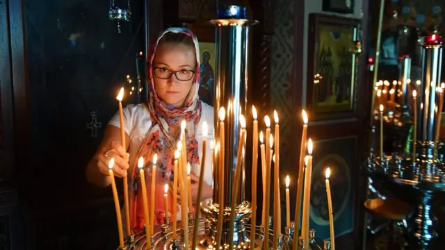 Прихожанка російської православної церкви Святої Богородиці в Сіднеї, Австралія, запалює свічку на Святвечір