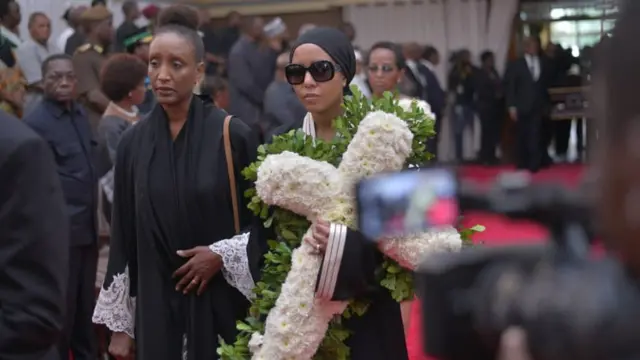 Mjane wa Dkt. Mengi, Jackline Ntuyabaliwe (mwenye shada jeupe la maua lenye muundo wa msalaba) akiingia katika ukumbi wa Karim Jee kwa ajili ya kuuaga rasmi mwili wa mumewe aliyefariki dunia mjini Dubai wiki iliyopita.