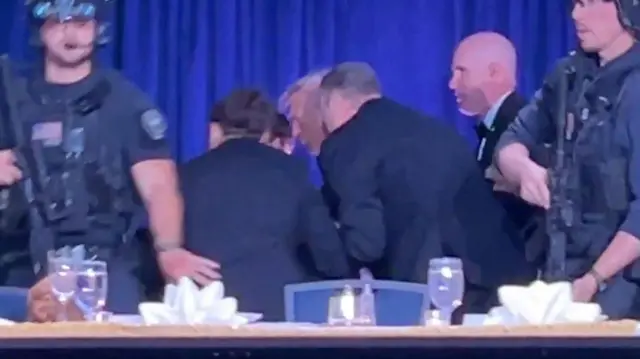 Donald Trump cercado por agentes de segurança
