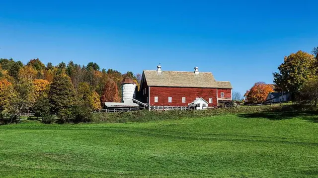 Granja rodeada de árboles con colores otoñales