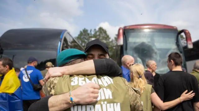 Звільнені з російського полону військові обіймаються біля автобусів