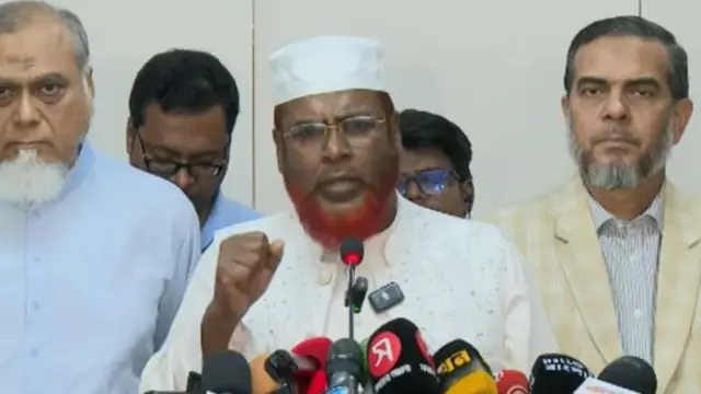 বাংলাদেশ জামায়াতে ইসলামীর সেক্রেটারি জেনারেল মিয়া গোলাম পরওয়ার সংবাদ মাধ্যমের সামনে কথা বলছেন। তার দুই পাশে ও পেছনে চারজনকে দেখা যাচ্ছে