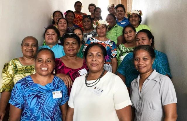 Dr Boreham gülümseyen, bazıları geleneksel kıyafetler giyen ve saçlarında çiçekler bulunan 20 kadın ile birlikte poz veriyor.