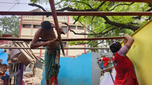 ভেঙে দেয়ার পর চালের কাঠামো খুলে নিচ্ছেন বাবা-মেয়ে