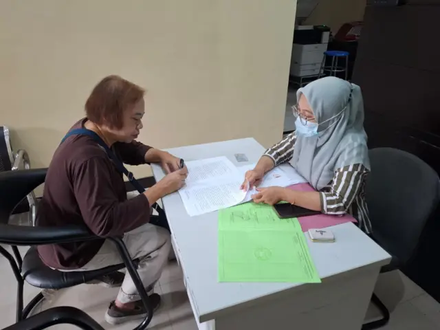 Dua tenaga kesehatan sedang duduk dalam satu meja.