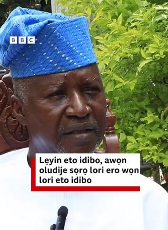 Dare Bejide, oludije gomina fẹgbẹ ADC nipinlẹ Ekiti wọ asọ toke tilẹ alawọ funfun pẹlu fila buluu, o joko lati ba akọroyin BBC News Yoruba sọrọ