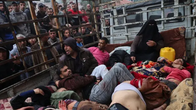 Wounded Palestinians in a lorry with a cage as people look at the from outside 