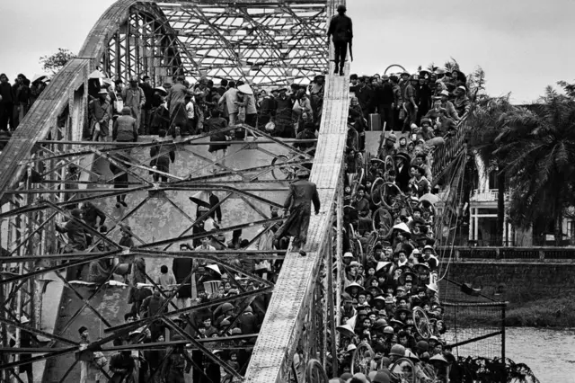 Thousands of civilians attempt to cross a bridge