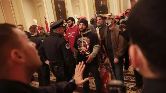 Os manifestantes falam com a polícia e outros funcionários do Capitólio durante um tenso impasse dentro