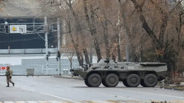 جندي كازاخي يسير على مقربة من مدرعة في ألماتي