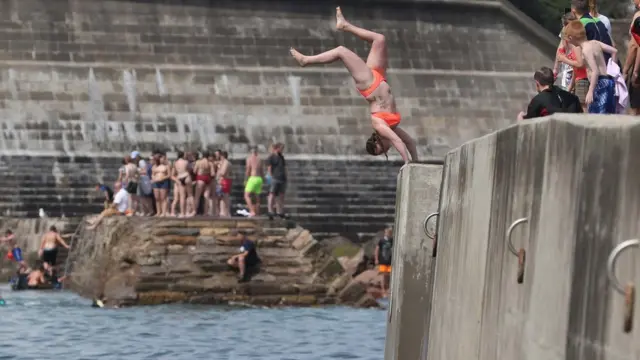A woman diving into the water at Cullercoats beach, North Tyneside