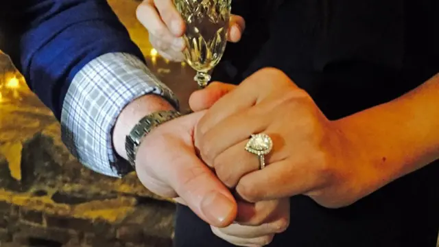 Dos personas dándose la mano. Ella lleva un anillo de compromiso