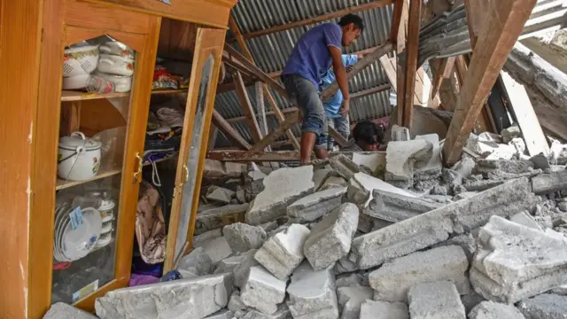 Warga mencari perlengkapan wisatawan asal Malaysia yang tewas tertimpa rumah roboh akibat gempa.