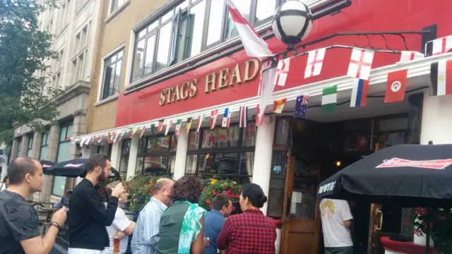 Penonton sampai meluber ke trotoar karena pub ini sudah penuh pengunjung.