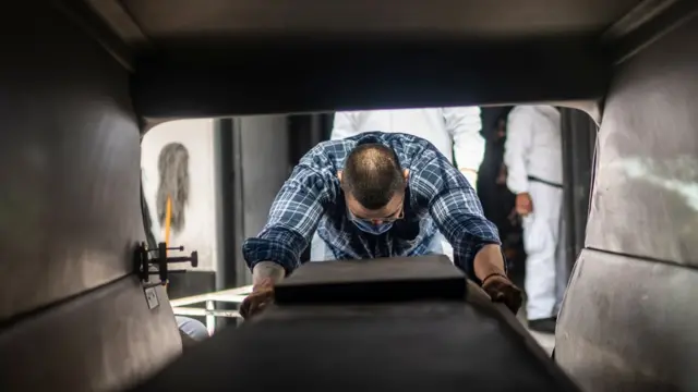 Hombre junto a un cajón fúnebre.
