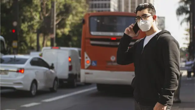 Homem falando no telefone enquanto espera transporte