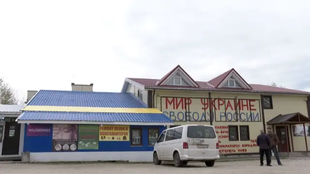 دميتري أمام واجهة دُكانه مع شخص آخر