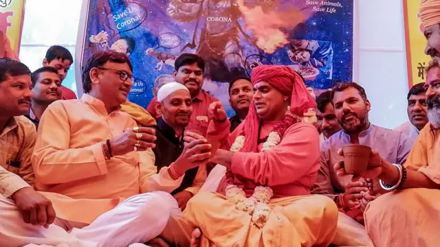 করোনাভাইরাস ঠেকাতে দিল্লিতে অখিল ভারত হিন্দু মহাসভার 'গো-মূত্র পার্টি'। সংগঠনের সভাপতি চক্রপাণি মহারাজ তার সমর্থকদের নিয়ে গরুর গোবর-মূত্র-দুধ এবং ঘি দিয়ে তৈরি পানীয় পান করছেন, ১৪ই মার্চ, ২০২০
