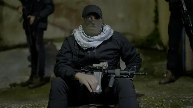 مجاهد مردی که ماسک زده و اسلحه‌ای در دست دارد