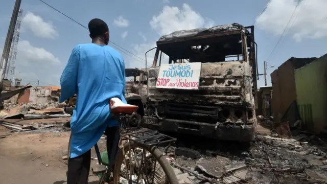 Umuntu atwaye ikinga ariko arasoma icapa kw'ikamyo yaturiwe gihamgarira abantu guhagarika ubugizi bwa nabi kw'isoko rya Toumodi itariki 4 z'ukwa cumi na rimwe 2020.