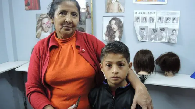 Niño de la escuela después de recibir un corte de pelo con Margarita, una de las estudiantes.