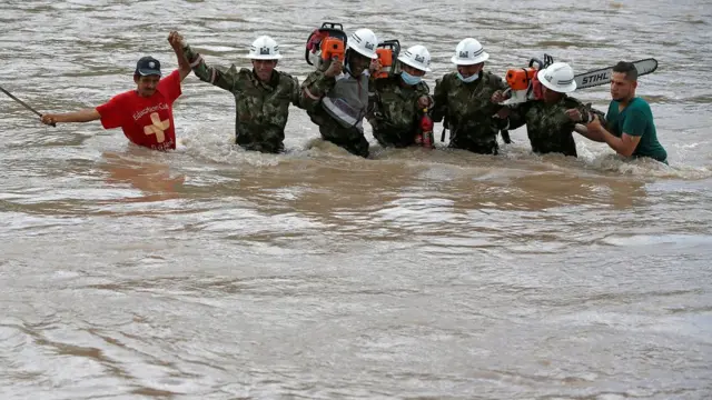 Hombres tratan de cruzar un río crecido en Putumayo
