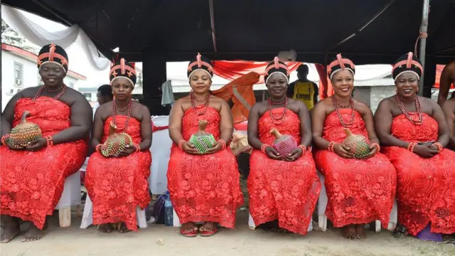 Mata sanye da tufafin gargajiyam, da murzani da tsakiya a hanny da wuya da kawunansu, zaune akan dogon benci. A hannayensu su na rike da gorar duma da aka kawata da duwatsu masu launi daban-daban.