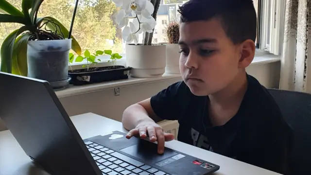 Menino Theo, diante do notebook