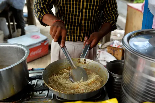దిల్లీ ఫుడ్ స్టాల్లో నూడుల్స్ సిద్ధం చేస్తున్న ఒక యువకుడు