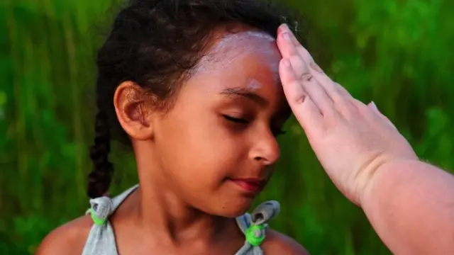 미국 친커티그 섬 '조랑말 수영 행사'에 참여한 한 어머니가 딸의 얼굴에 자외선 차단제를 발라주고 있다