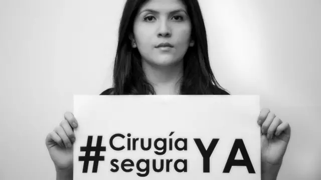 Lorena Beltrán sosteniendo un cartel de su campaña #CirugíaSeguraYA