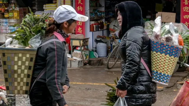 Des femmes Naxi locales portent des paniers en osier tissé sur le marché de la province du Yunnan, en Chine