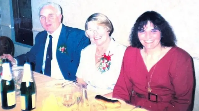 Brian, Mavis Wilson e uma convidada sentados diante da mesa