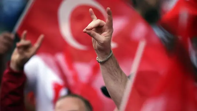 Рука приказује главу вука. Кажипрст и мали прст формирају уши, палац, средњи и домали прст формирају нос и уста.