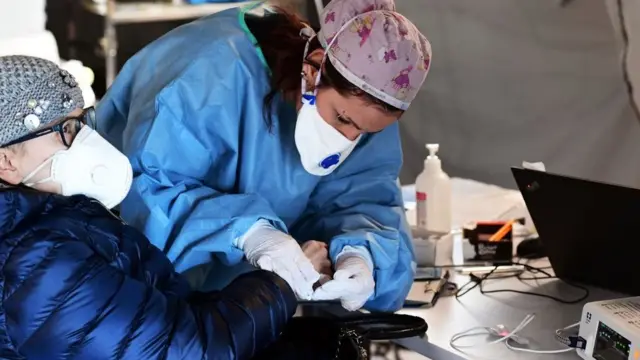 Una médica atendiendo a un hombre.