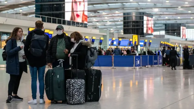 People in face masks stand in airport