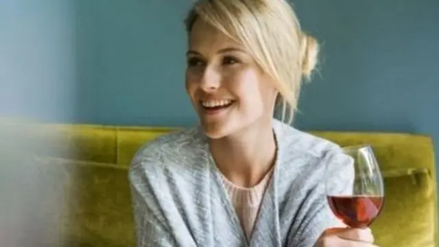 हातात वाईनचा ग्लास असलेली महिला