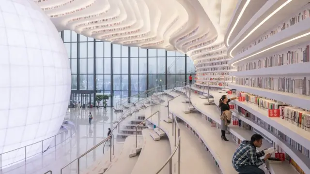 Dos personas consultan libros en la biblioteca.