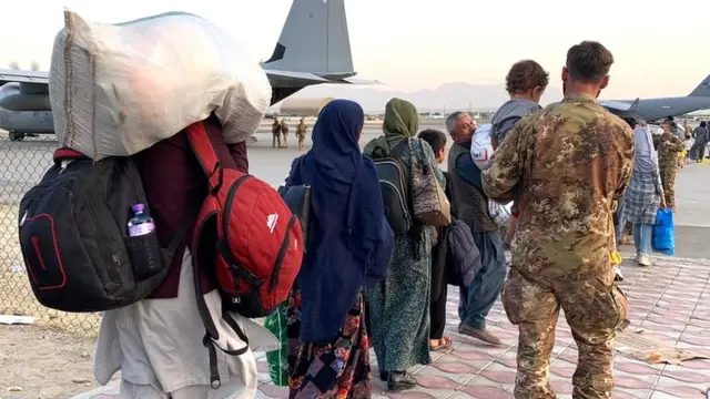 Personas caminando con sus pertenencias en el aeropuerto de Kabul.