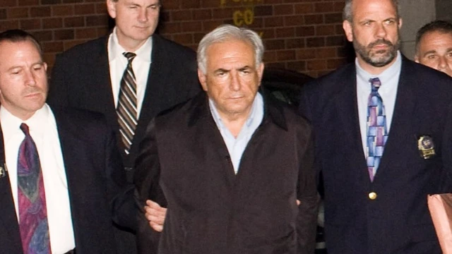 رئيس صندوق النقد الدولي دومينيك شتراوس كان ، مكبل اليدين ، مشياً على الأقدام إلى سيارة شرطة خارج مرفق إدارة شرطة مدينة نيويورك