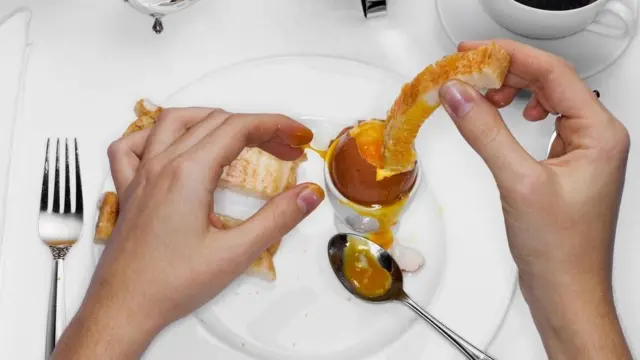 Una persona mojando un pedazo de pollo frito en una salsa