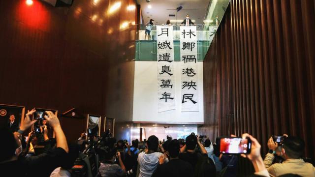 香港立法會大樓內民主黨原議員林卓廷（上層右一）在媒體面前展示大型抗議標語（12/11/2020）