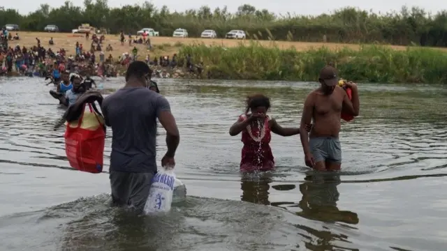 Migrants, many of them Haitian, cross the Rio Grande river from the United States back to Mexico