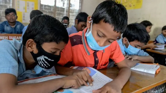 માસ્ક પહેરીને શાળામાં બેઠેલા વિદ્યાર્થીઓ