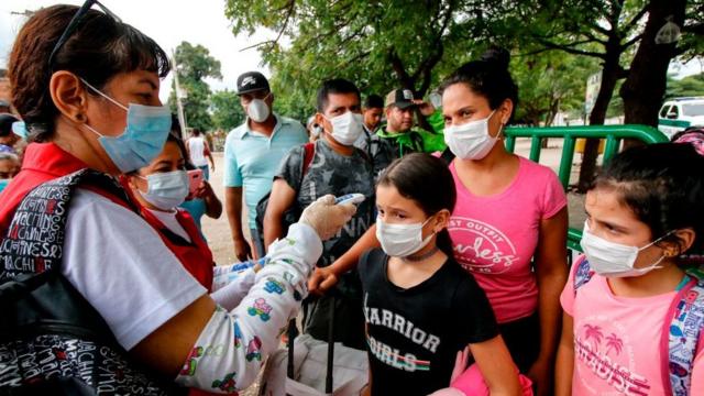 Mujer tomándole la temperatura a niños en la frontera entre Venezuela y Colombia