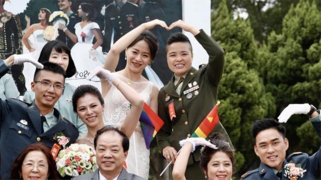 同婚新人少校政戰官王翊和伴侶孟酉玫拿著彩虹旗參加婚禮（Credit: EPA）