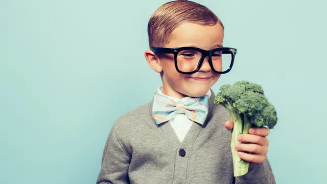 Un niño agarrando un brócoli