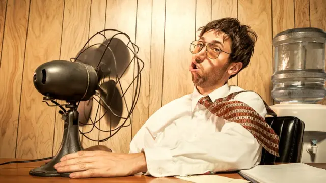 Hombre en la oficina frente a ventilador.